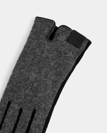 A close-up of the Rudsak OLGA - L425541 Grey women’s wool glove, featuring black detailing and a leather label by the wrist—an essential for style and warmth, shown against a plain light background.