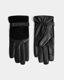 The PARKER - M425502 Black men’s leather gloves by Rudsak feature suede detailing and a buttoned strap, displayed flat on a light gray background—an ideal choice for stylish winter wear.