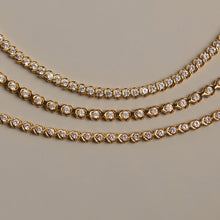 Flatlay Model. Gold necklaces with diamond accents on a beige background