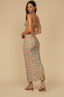 Woman wearing a colorful floral print slip dress with thin straps and an open back, paired with brown heeled sandals.