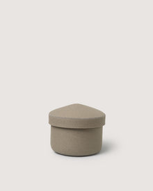 A small, beige Graf Lantz merino wool bin with a fabric cover, round base, and triangular rounded lid sits against a plain light background.