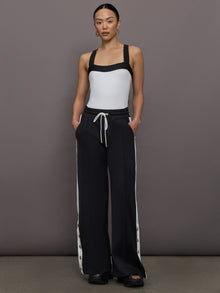 Model wears a high cut one piece square neck bathing suit in white with black edges. 