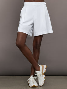 Model wears a pair of white pleated culotte wide leg mid rise waisted shorts. 