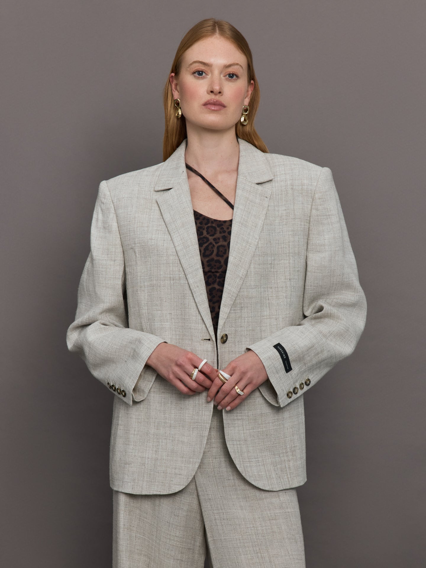 Model wears a gray/taupe textured oversized blazer with single button closure.