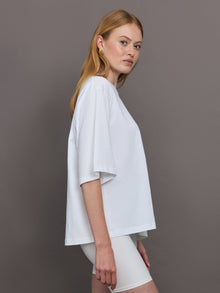 Model wears an oversized wide sleeve white tee shirt with red Herskind lettering across the chest.
