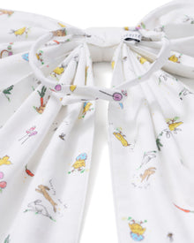 An Easter Basket and Wreath Bow in Easter Frolic with a large white bow featuring a pastel floral pattern is tied at the bottom of a wreath made of small white and pink flowers, hanging on a beige door.