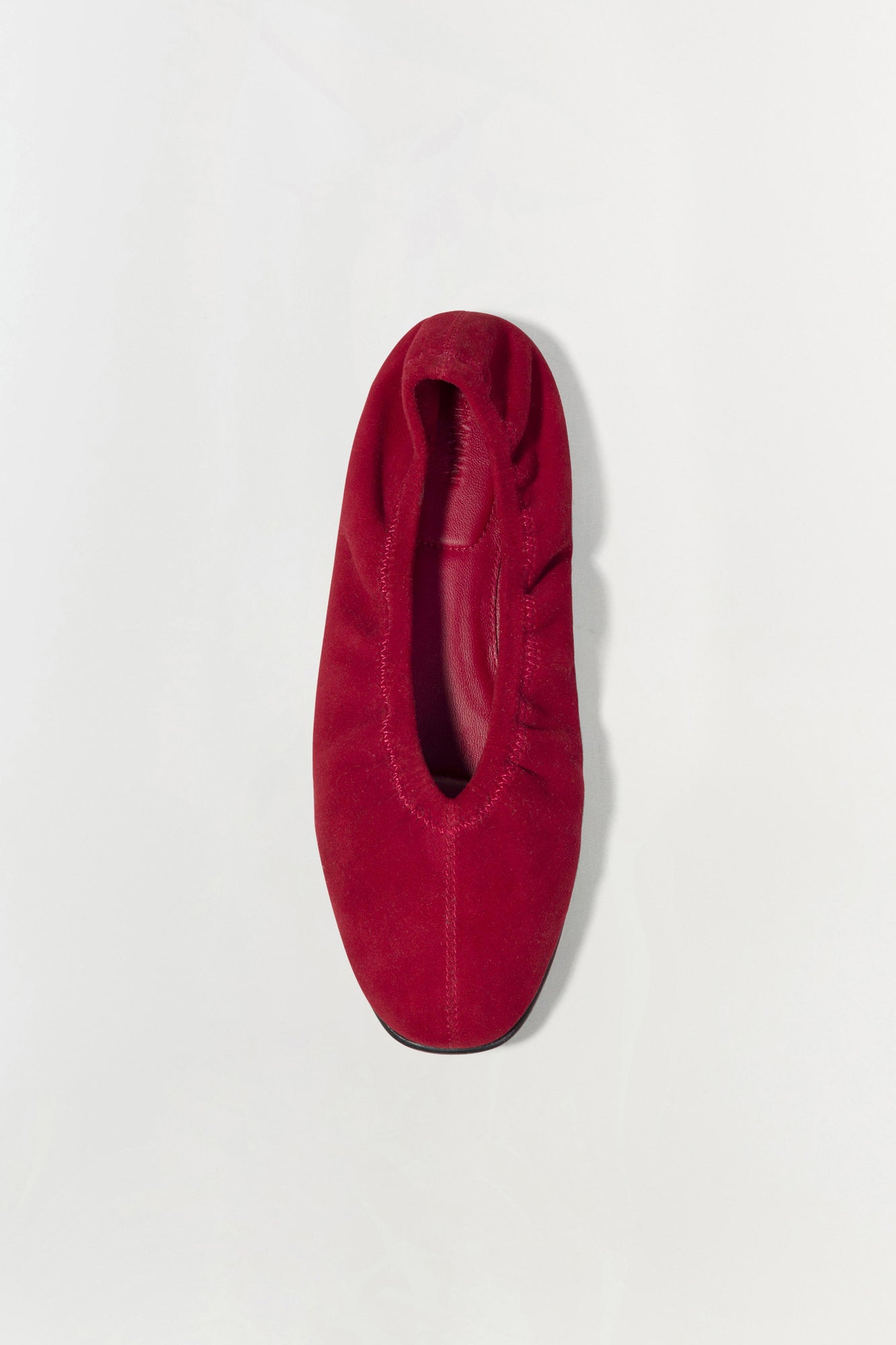 Burgundy suede ballet flat shown from above with rounded toe and dark sole.