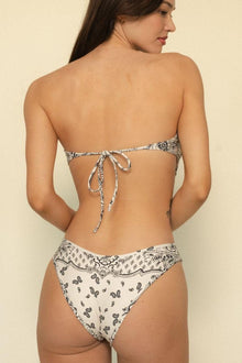 Cream bikini bottom with black bandana print and ruched sides, shown from back view.