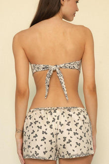 Bandeau bikini top with cream and black paisley print, tie-back closure, shown from rear view on model.