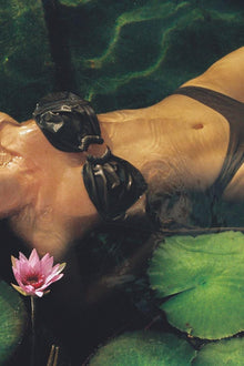 Khaki bikini bottom with black zig-zag stitching detail worn in water with lily pads.