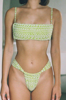 Lime green and white patterned bikini top with thin shoulder straps and textured abstract design.