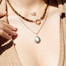 Model. Close-up of a person wearing two necklaces with a focus on the pendant details.