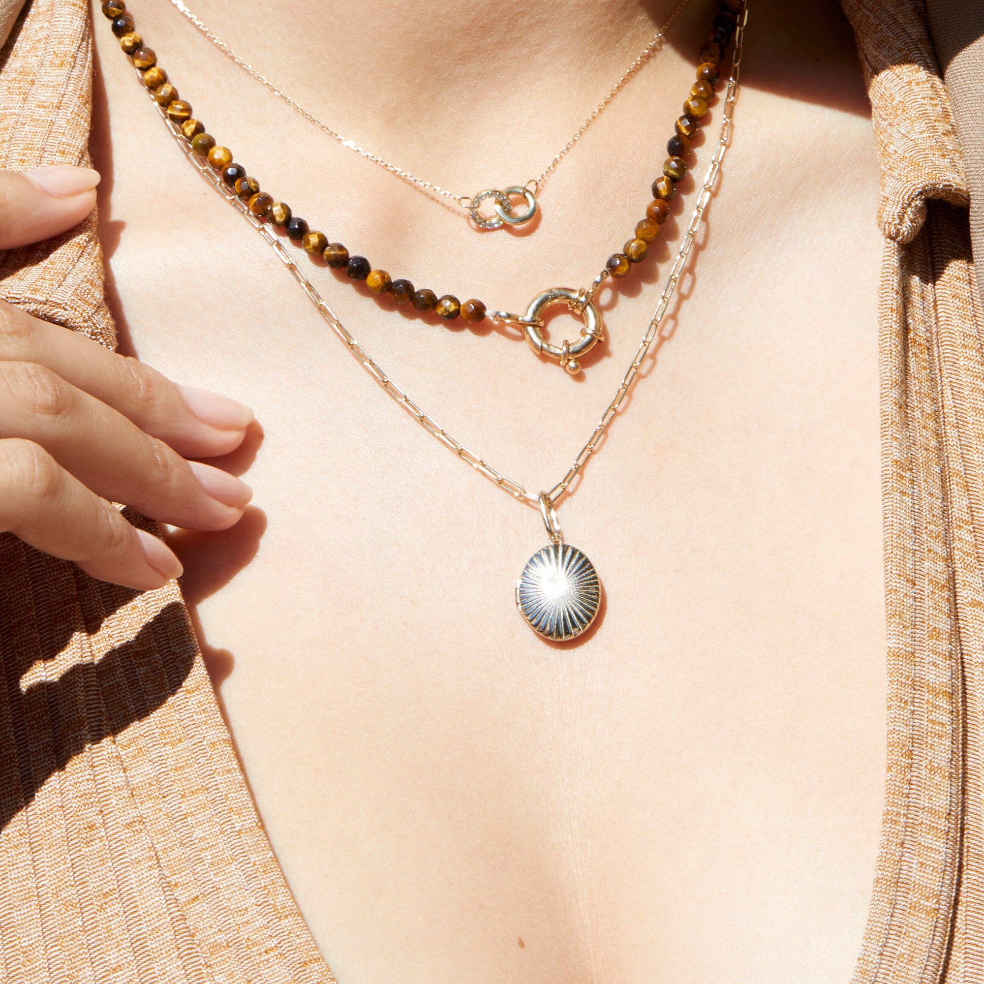 Model. Close-up of a person wearing two necklaces with a focus on the pendant details.
