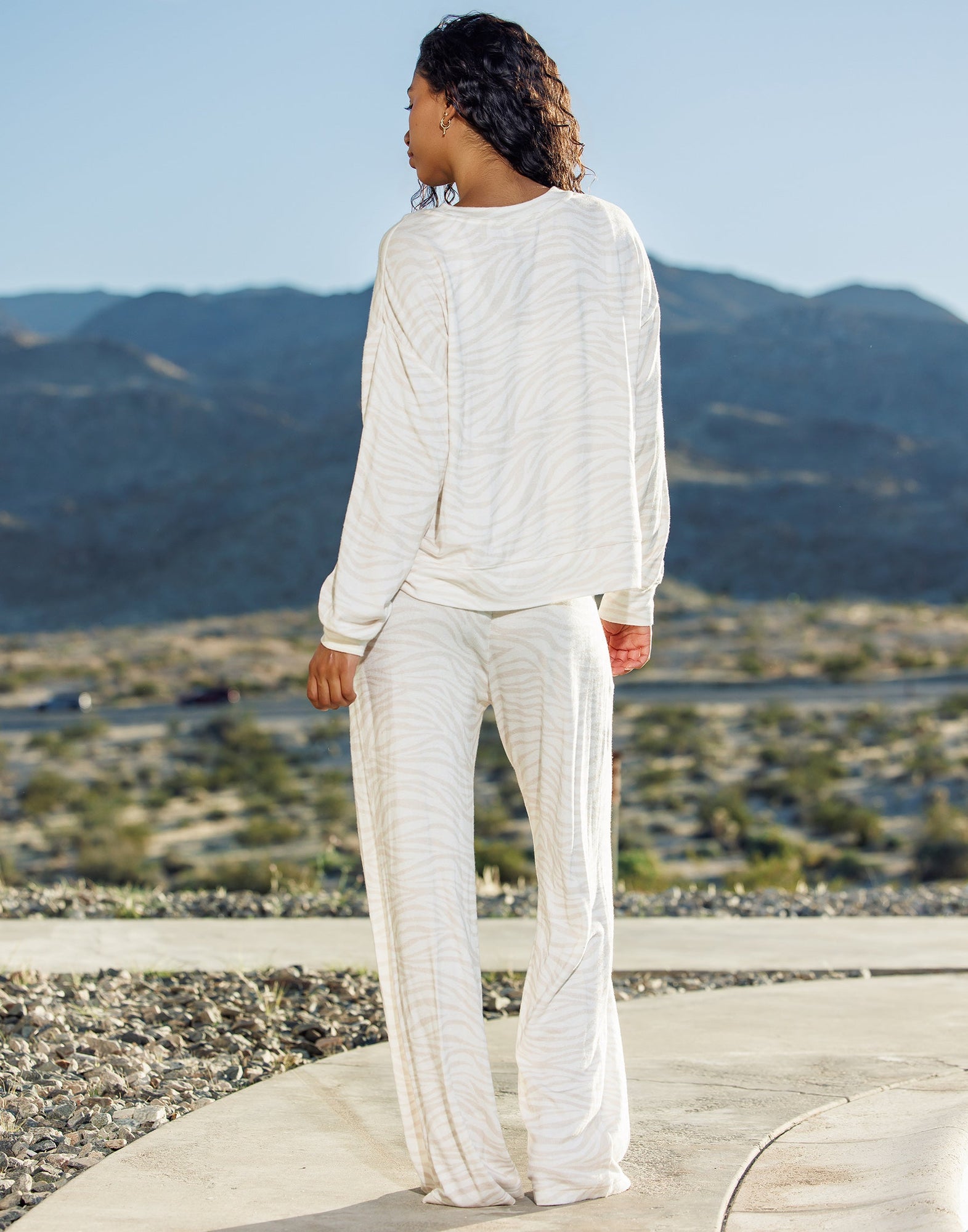 Person wearing a white outfit standing on a rooftop with mountains in the background