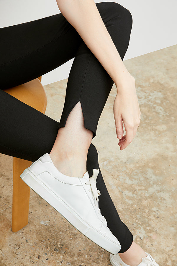 Front image of a woman wearing the skinny foster in black showing off the slit at the ankle of the pant | Exclude