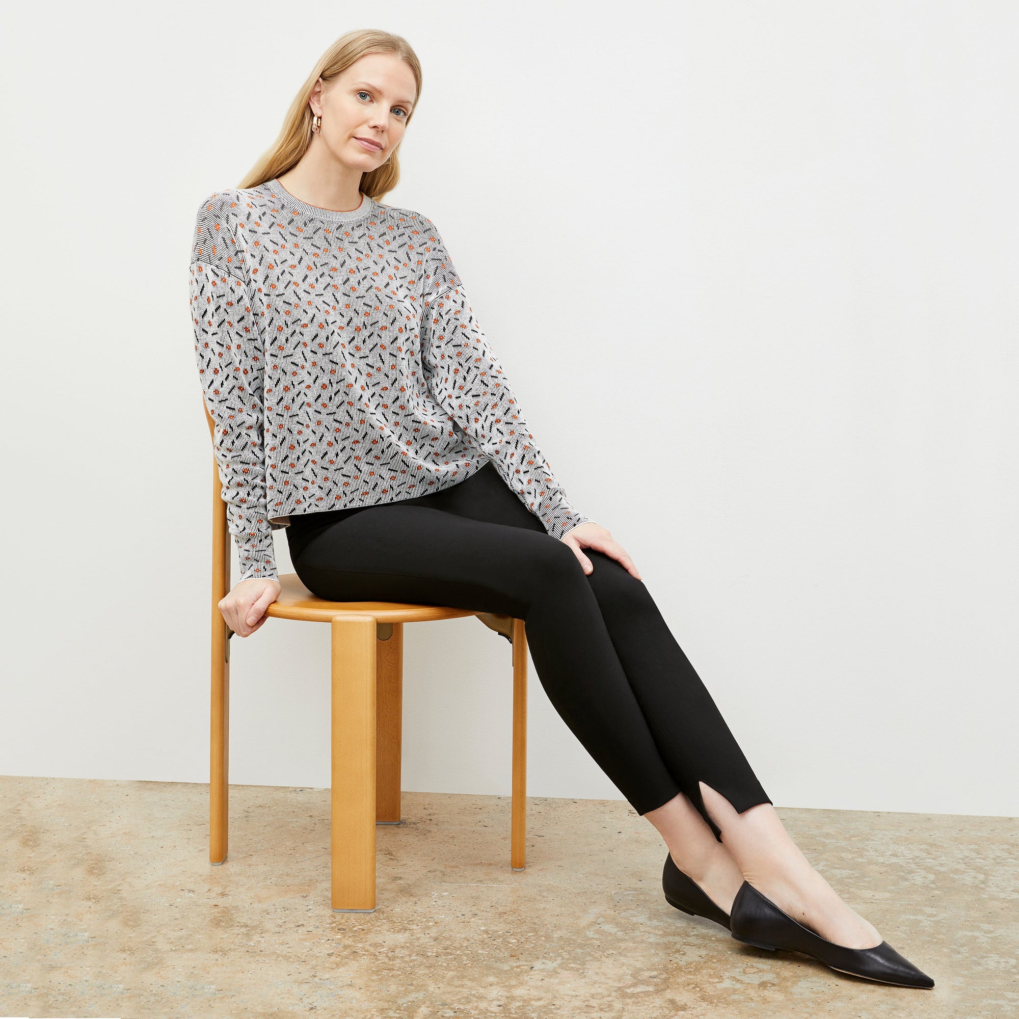 Front image of a woman sitting wearing the skinny foster in black | Exclude