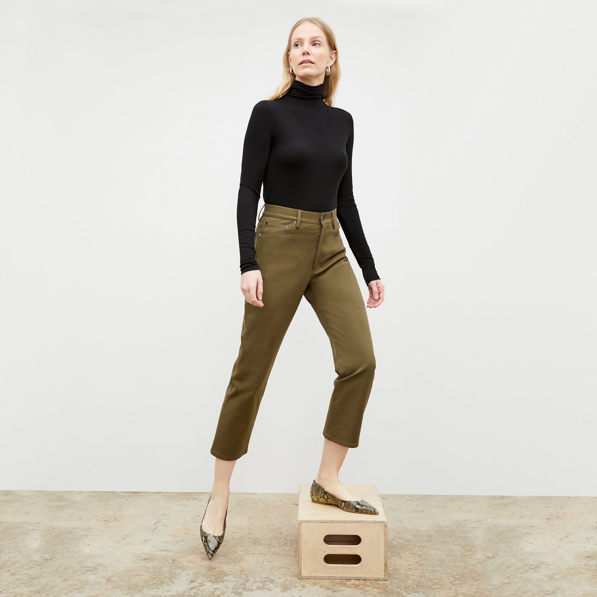 Front image of a woman standing wearing the axam top in black | Exclude
