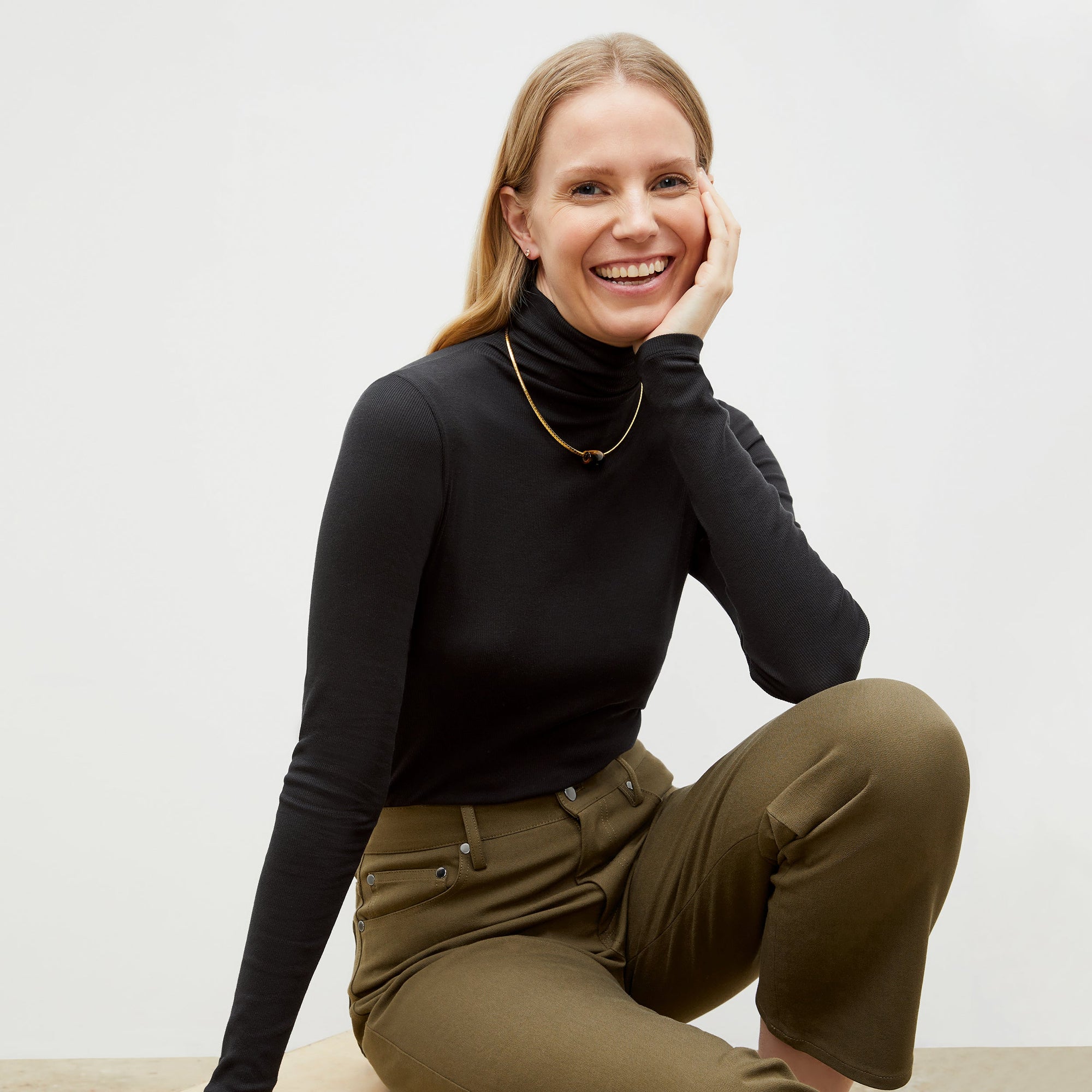 Front image of a woman standing wearing the axam top in black | Exclude