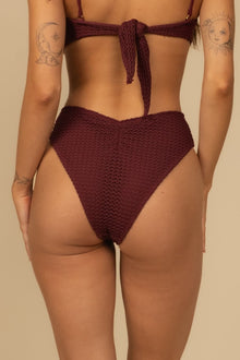 Maroon crochet bikini bottom with textured knit fabric and high-waisted cut shown from back view.