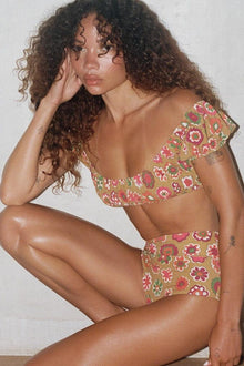 Floral bikini top with pink, red, and green flowers on tan background and ruffled neckline.