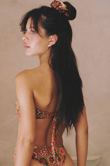 Bandeau bikini top with multicolored floral print and tie closures at back, shown from behind on model.