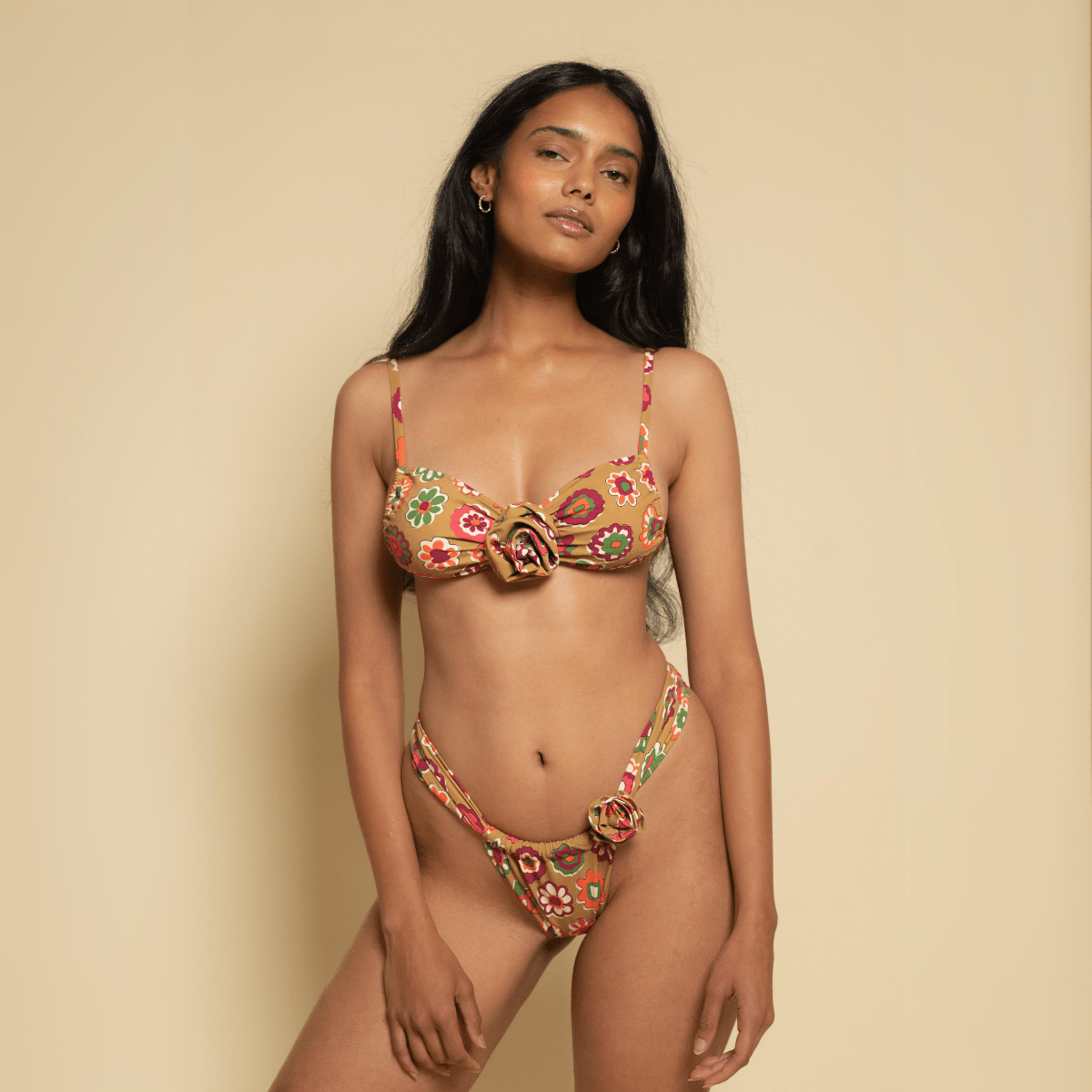 Woman wearing multicolored floral bikini with gold rose-shaped hardware details on chest and hip areas.