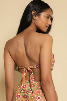 Bandeau bikini top with colorful floral print on tan background, featuring tie closure at back.
