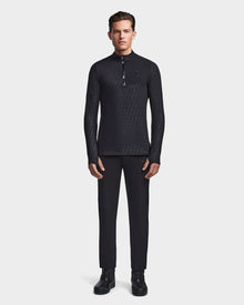 A man faces forward, wearing the Rudsak WARREN - 6523502 Black Pattern fitted stretch top—a black zip-front mock neck long-sleeve shirt—paired with black trousers and black lace-up shoes against a plain white background.