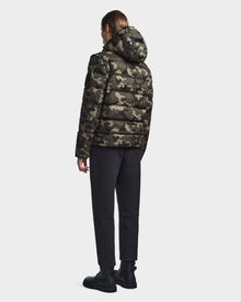 A person faces away, wearing the Rudsak DEMIAN M-R - M123504 Camouflage mens down puffer with a hood, paired with black pants and boots, set against a plain light background.