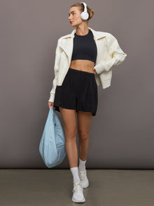 Model wears a pair of black pleated high rise athleisure shorts. 
