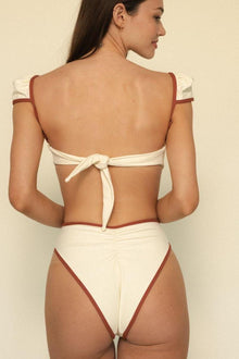 Oat and terracotta bikini bottom with bound edges, shown from back view on model.