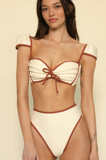 Oat and terracotta bikini bottom with contrast binding trim and high-cut leg openings.