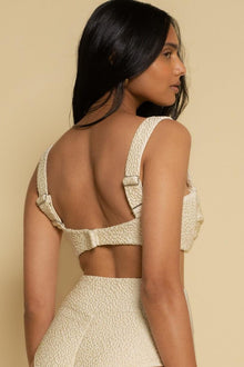 Oat-colored textured bikini top with thick shoulder straps and underwire cups, shown on model from back view.