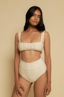 Oat-colored textured high-rise bikini bottom with curved waistband and full coverage back.