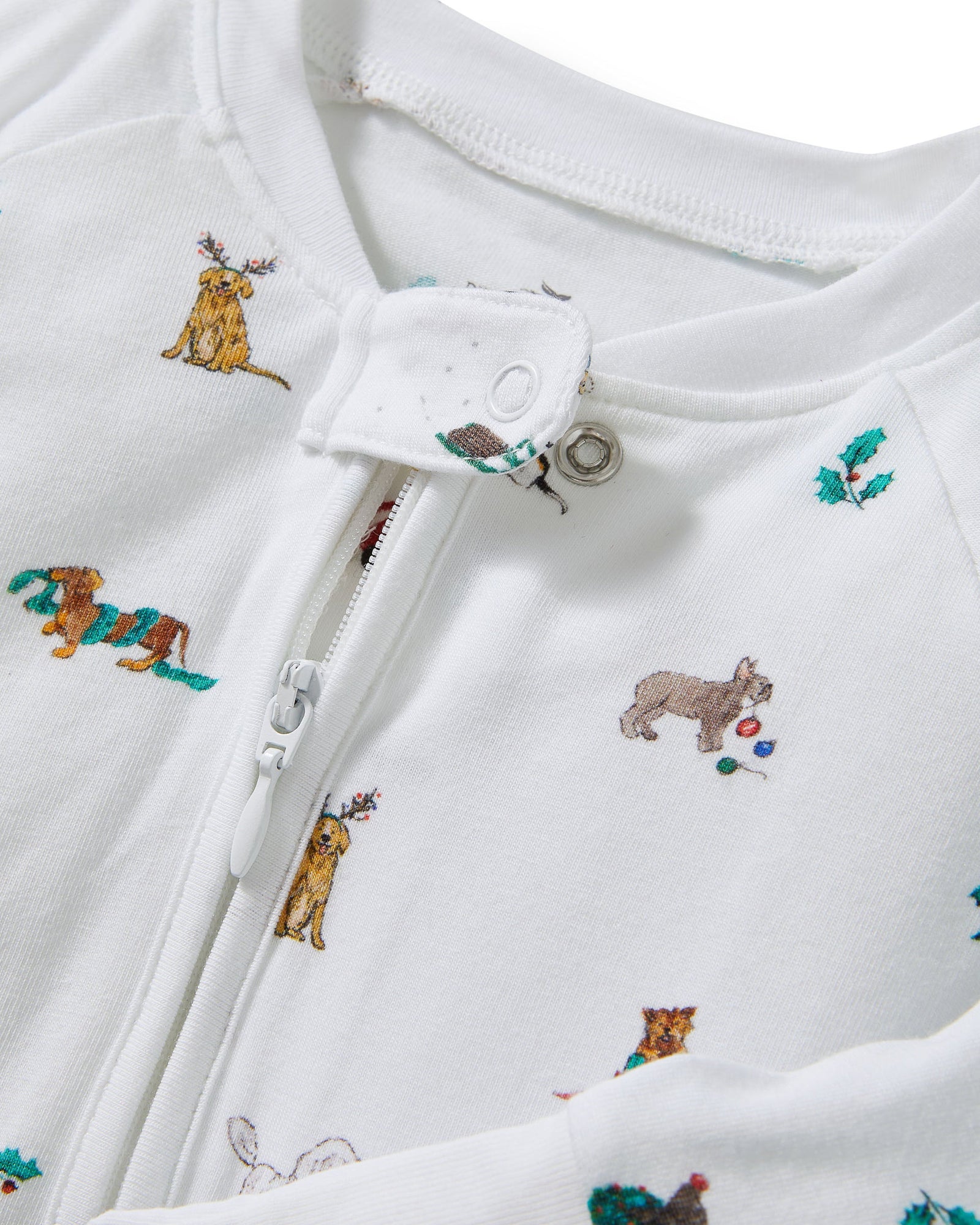 The Baby's Pima Peekaboo Romper in Jingle Paws is a white, long-sleeve onesie with a front zipper, decorated with colorful dogs and green bones. The left leg appears slightly folded over.