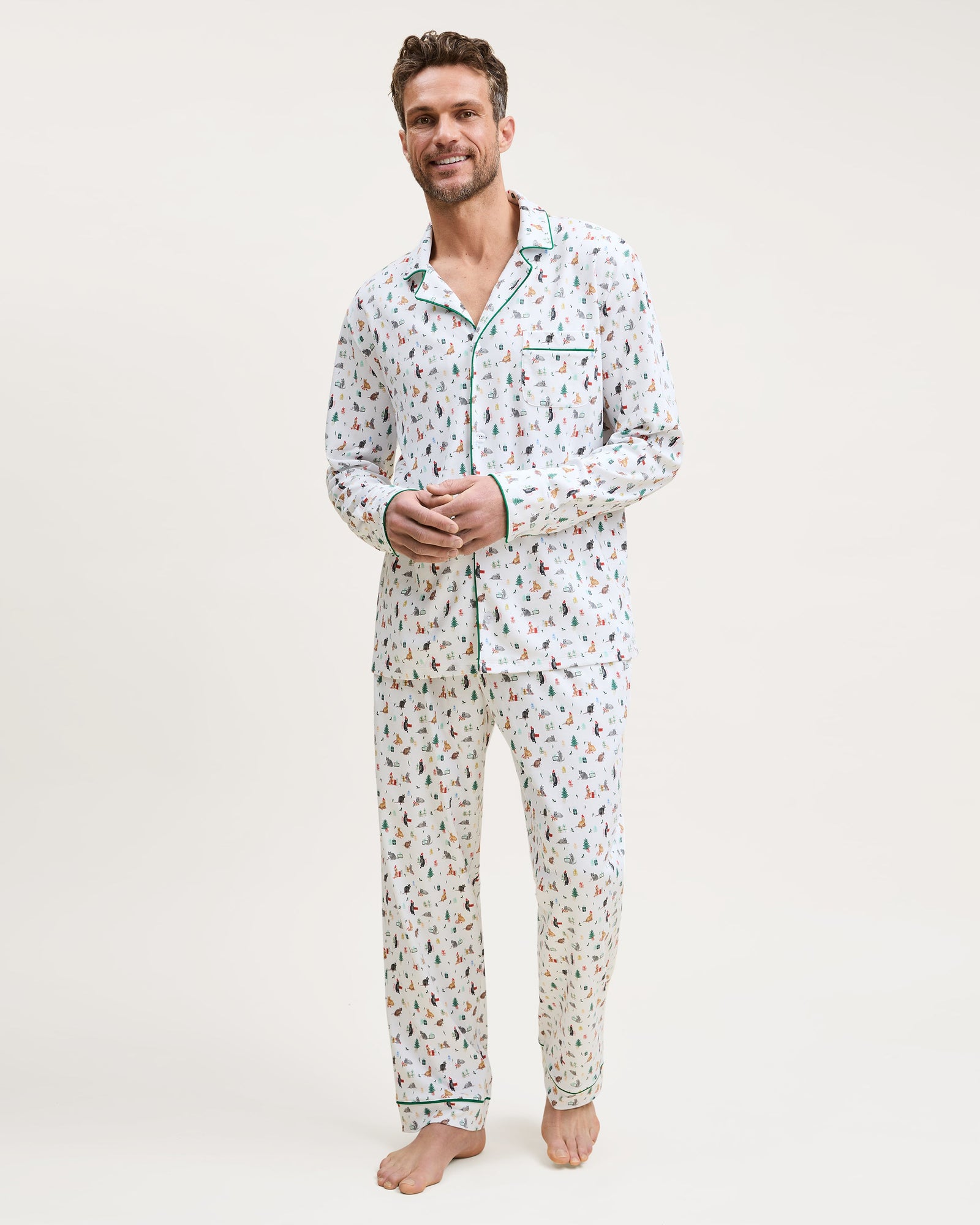 Men's Pima Pajama Set in Merry Meow: white set with green piping, featuring an all-over print of playful colorful cats. Includes a long-sleeve button-up shirt with chest pocket and matching pants.