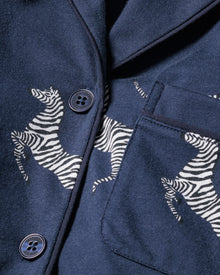 Close-up of Petite Plumes Womens Pima Pajama Set in Zebre de Nuit, a dark blue ensemble adorned with a zebra print. Crafted from luxurious Peruvian Pima cotton, it showcases exquisite texture with refined details like buttons and a pocket.