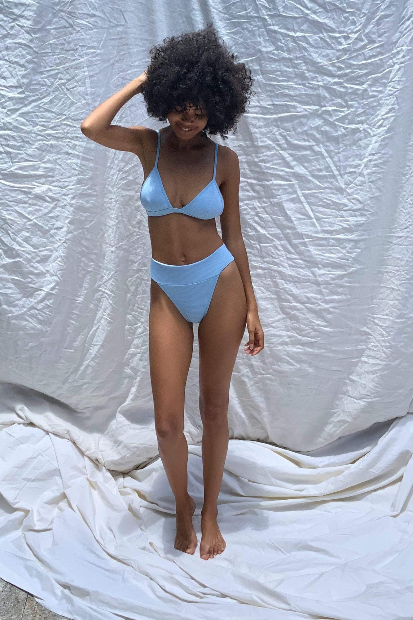 Light blue triangle bikini top with adjustable spaghetti straps and V-neckline on model.