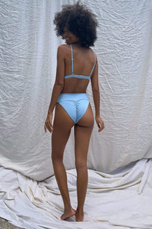 Light blue ribbed triangle bikini top with thin shoulder straps, shown from back view on model.