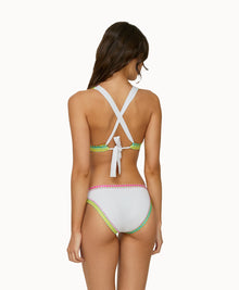 Back view of woman wearing a white crochet bikini in front of a white background. 