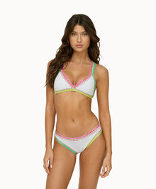 Woman wearing a white crochet bikini in front of a white background. 