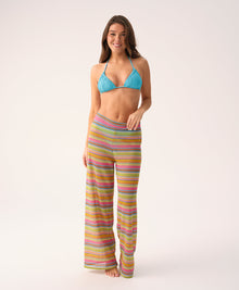 Woman wearing a blue bikini top and colorful striped pants on a white background