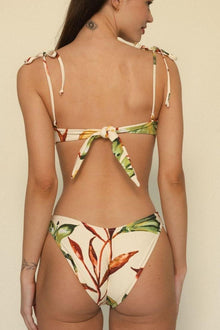 Bikini bottom with cream background and multicolored leaf print, featuring zig-zag stitching and higher leg coverage.