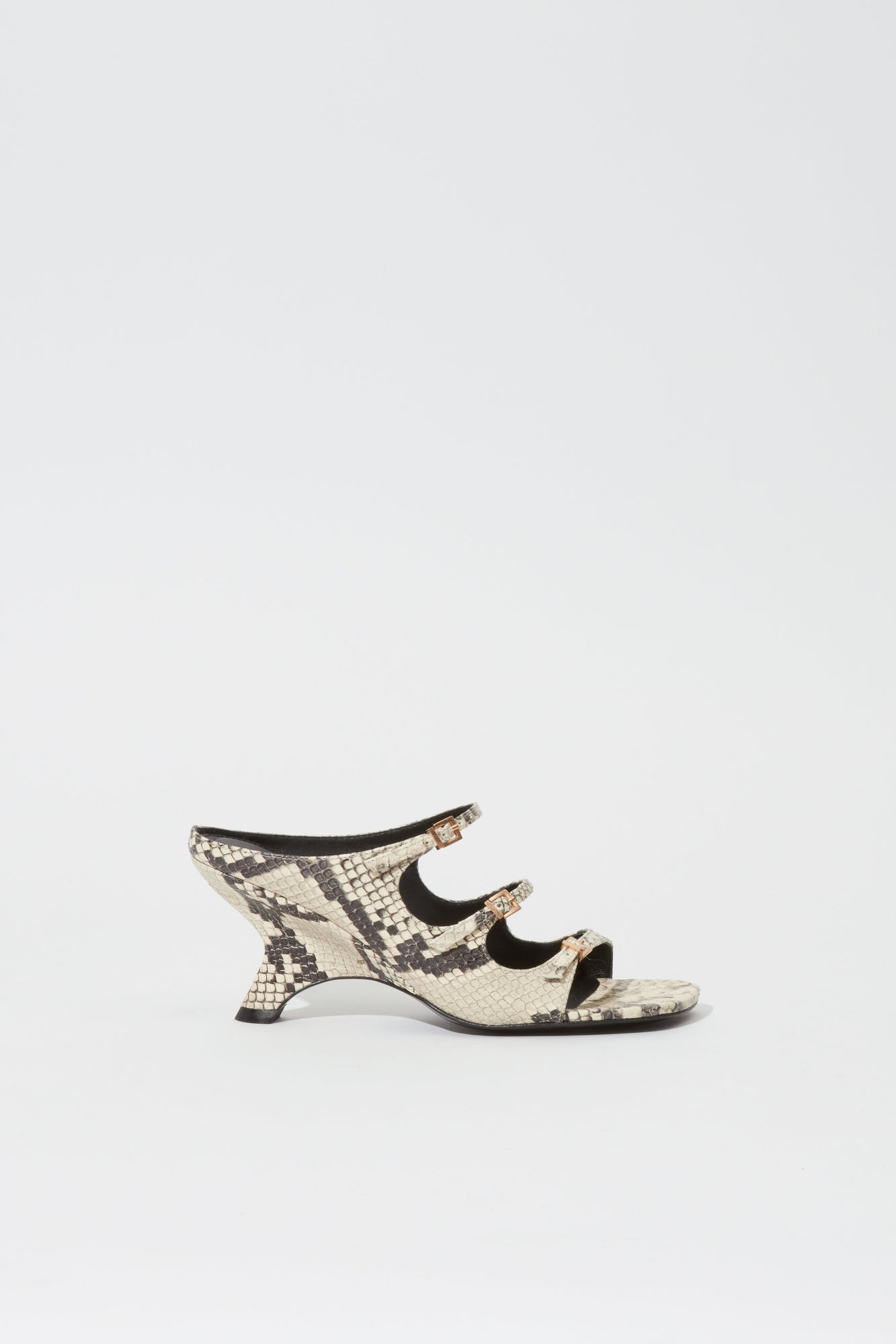 Cream and black snake print leather mule with buckle straps and curved heel, shown in profile.