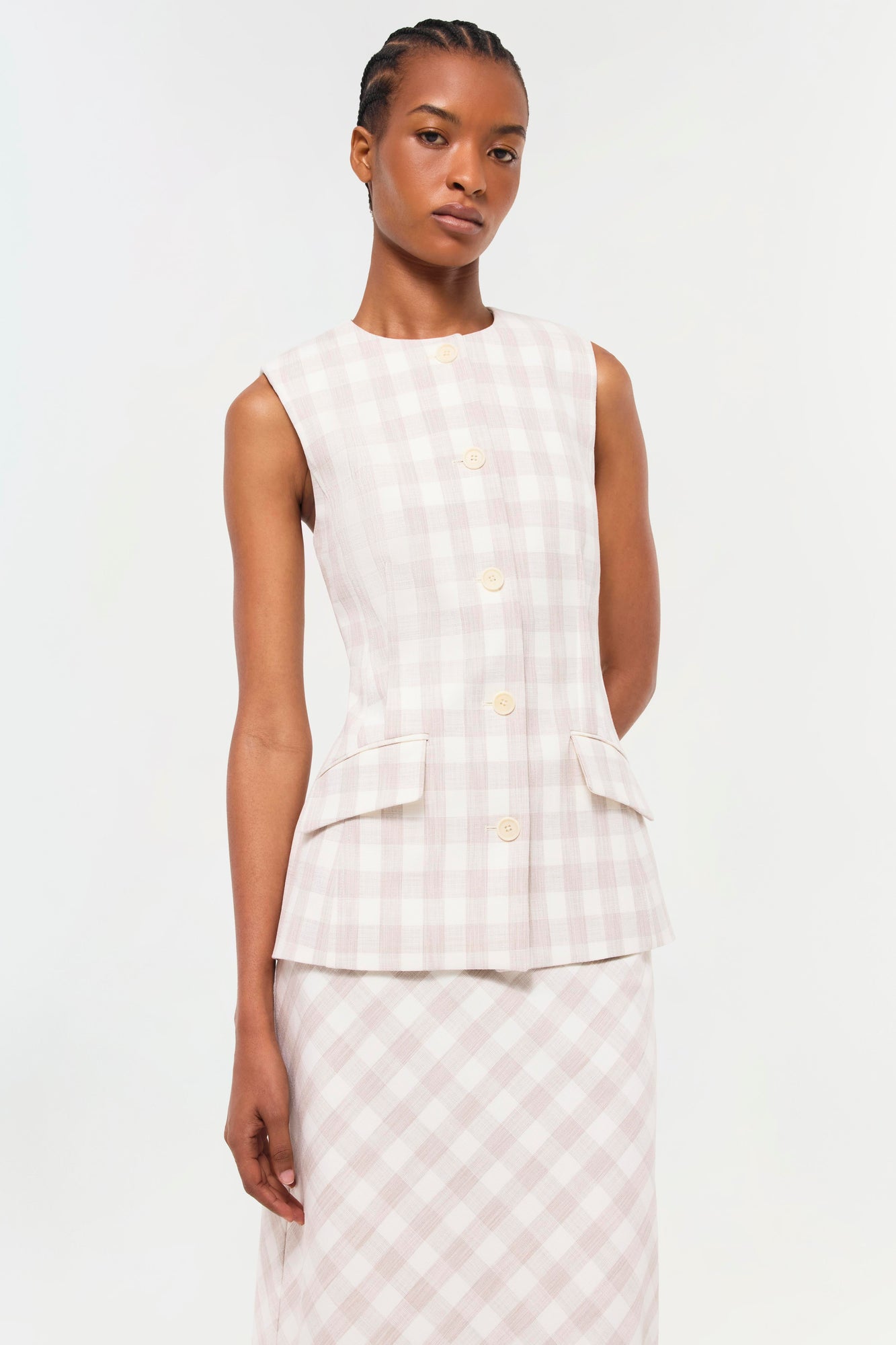 Sleeveless button-front vest in pale pink and white gingham with side pockets, worn with matching skirt.