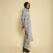 Gray and white striped knit scarf draped over person's shoulder, extending to ankle length.