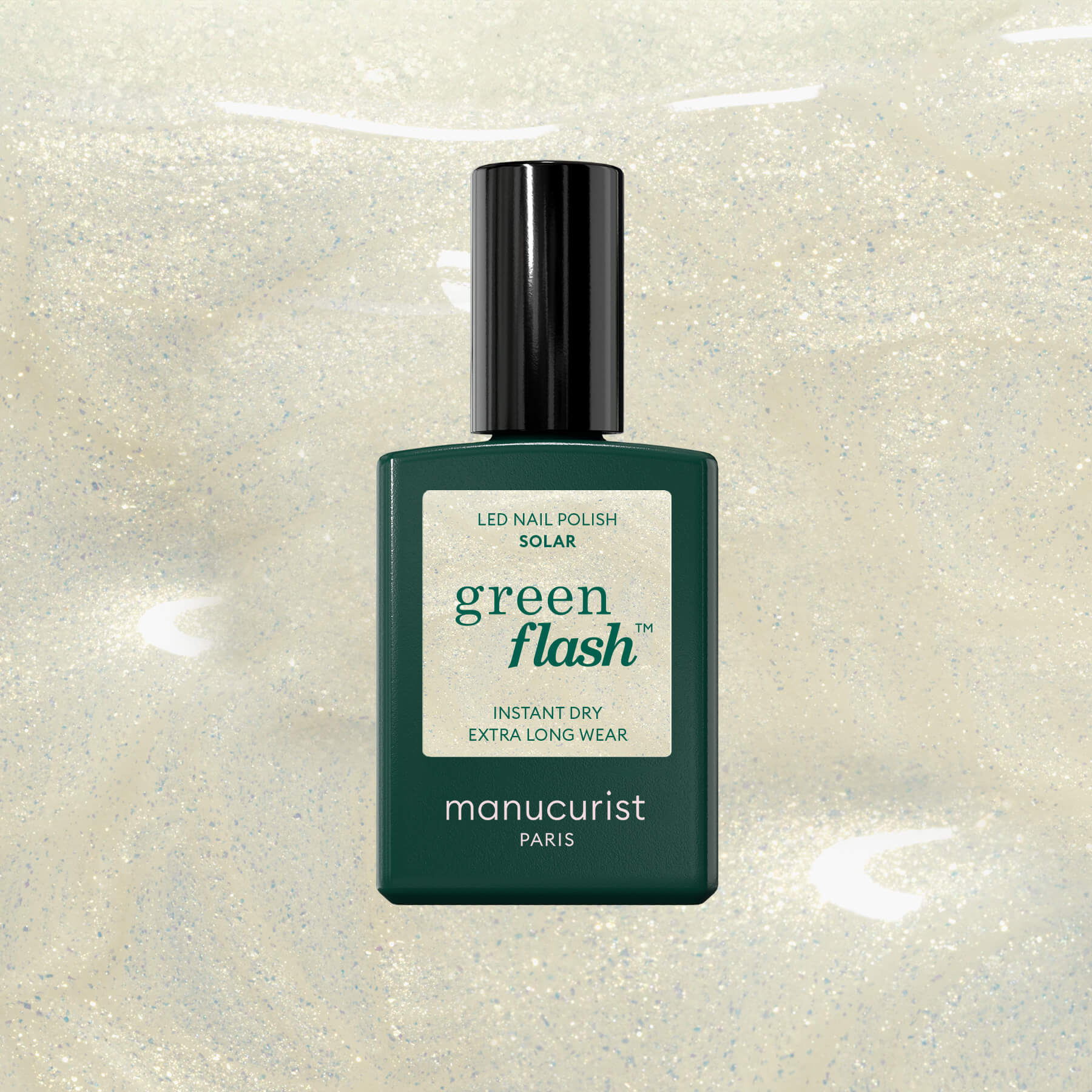 A dark green bottle of Manucurist Paris Green Flash LED nail polish stands upright on a shimmery, light beige background. The label highlights Instant Dry Extra Long Wear with solar LED technology.