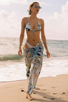 Wide-leg pants with blue and multicolor floral print and drawstring waist on model at beach.