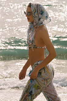 Woman wearing floral drawstring wide-leg pants with matching headwrap at the beach.