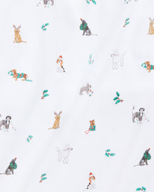 The Kids Pima Snug Fit Pajama Set in Jingle Paws by Petite Plume features a playful dog pattern with festive accessories on soft Pima cotton. The long sleeve top and pant set displays pups carrying presents amid holly leaves on a crisp white background.